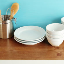 Close-up of a counter with dinnerware and utensils with our Creative Covering in teal as a backsplash